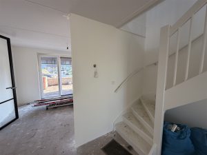 Hal met trap en doorkijk naar de woonkamer, wanden met renovlies gesausd