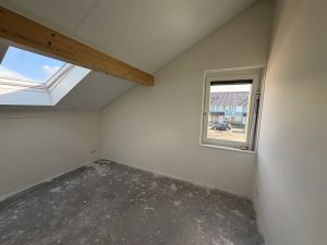 Zolder met dakraam en schuine wanden, afgewerkt met renovlies en wit gesausd